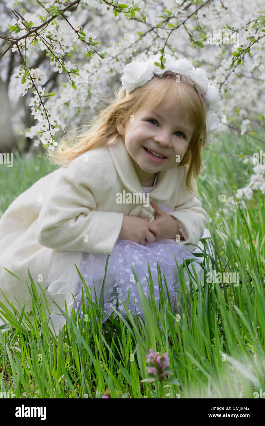 Smiling girl sitting among spring blossom garden Stock Photo - Alamy