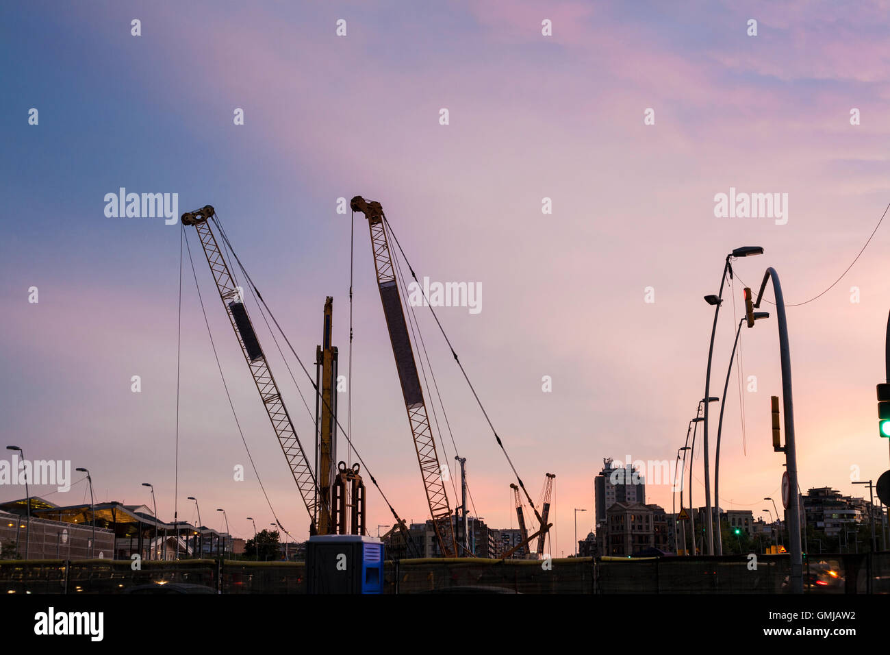 Cranes silhouettes of subway line over colorful sunset sky Stock Photo