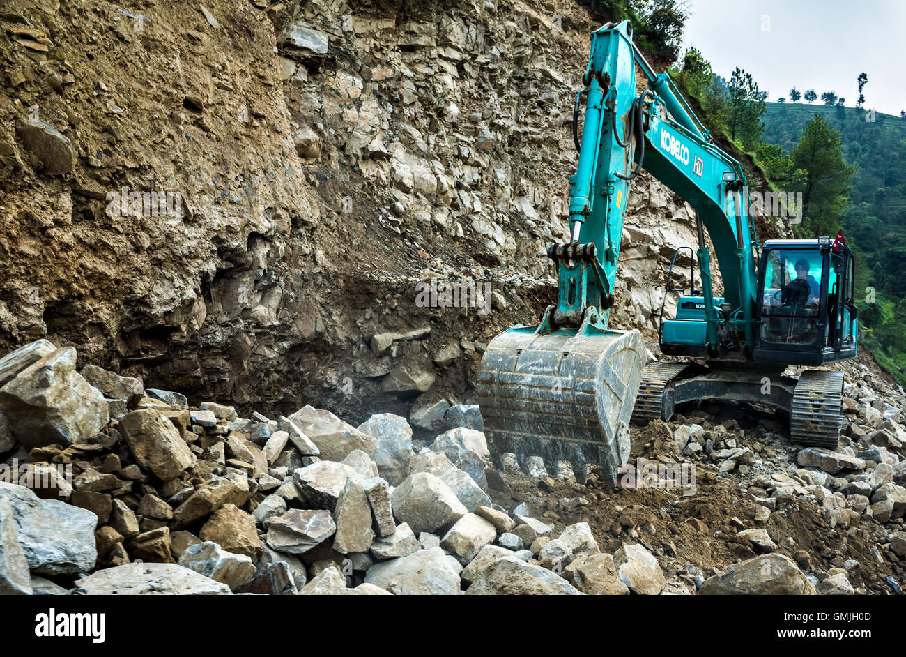 an excavator at work on a hill road construction site near Sisnery, Makawanpur, Nepal Stock Photo
