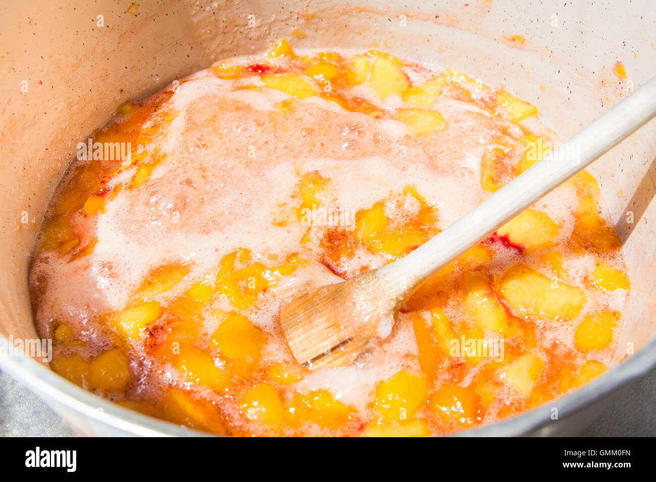 Top view of a pot full with simmering peaches. Homemade peach jam cooking. Stock Photo