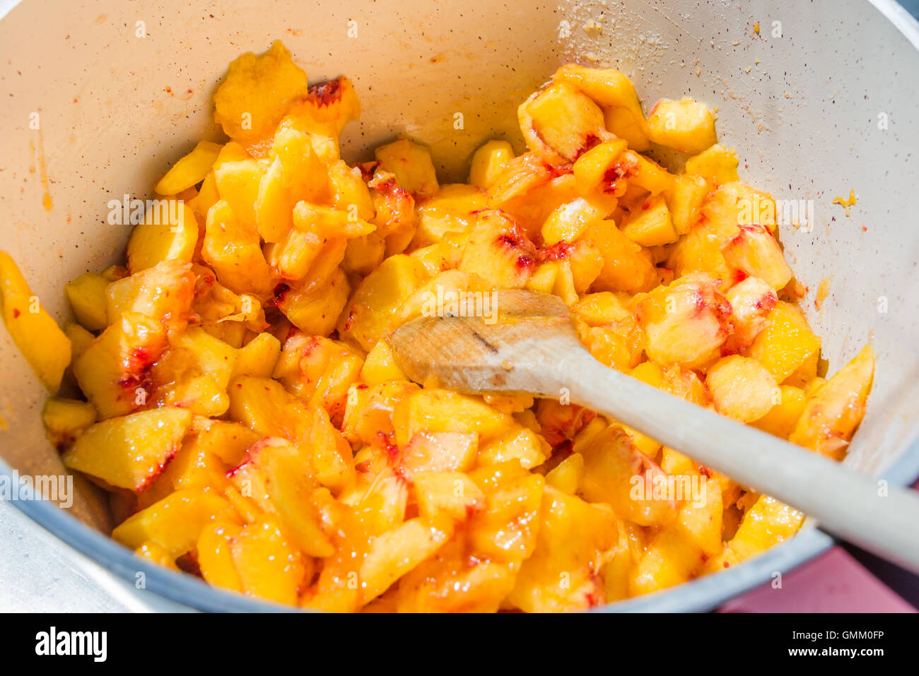 Top view of a pot full with cut peaches. Homemade peach jam cooking. Stock Photo