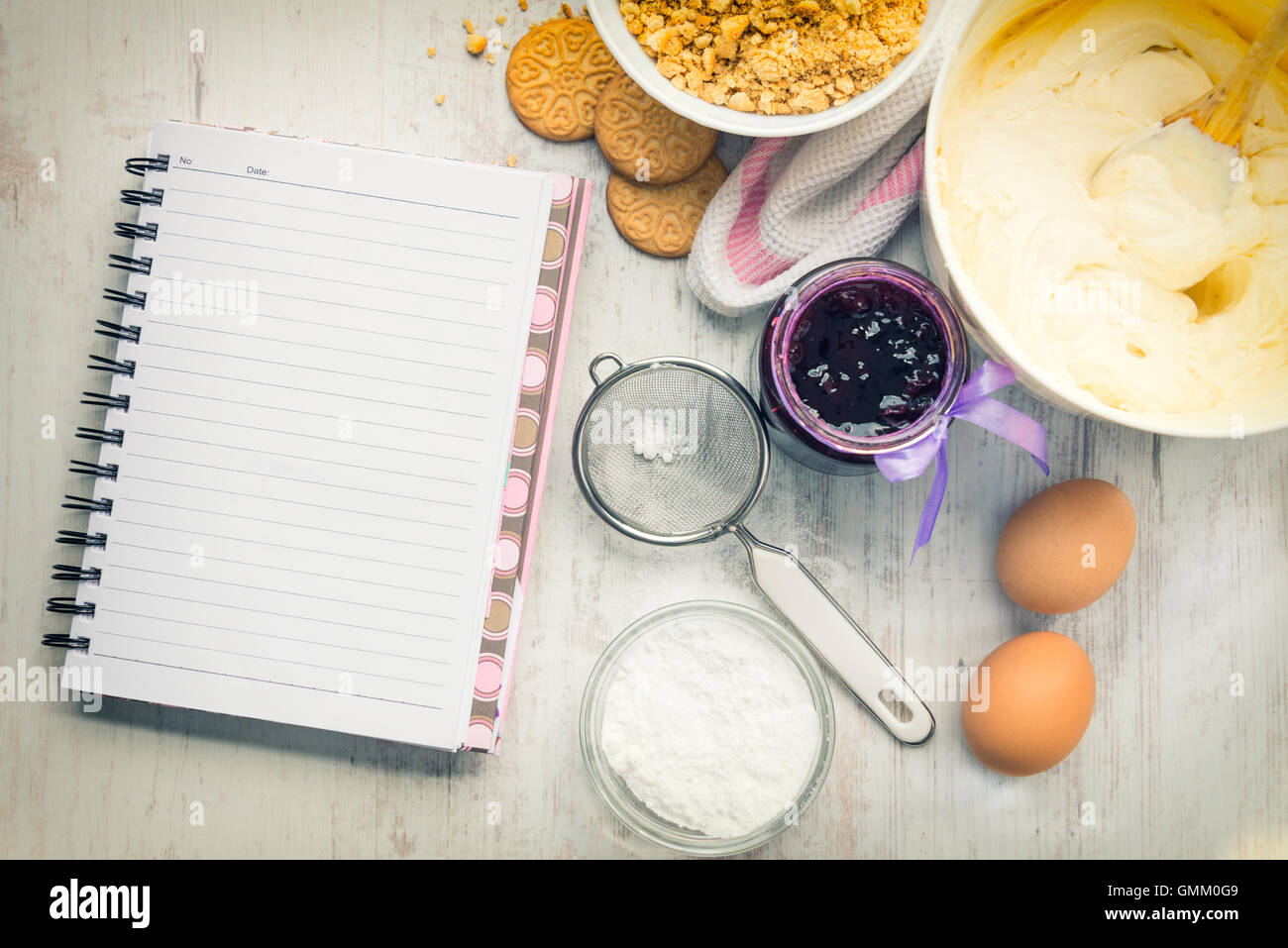 Empty recipe notebook with cheese cake ingredients prepared over a white wood background. Stock Photo