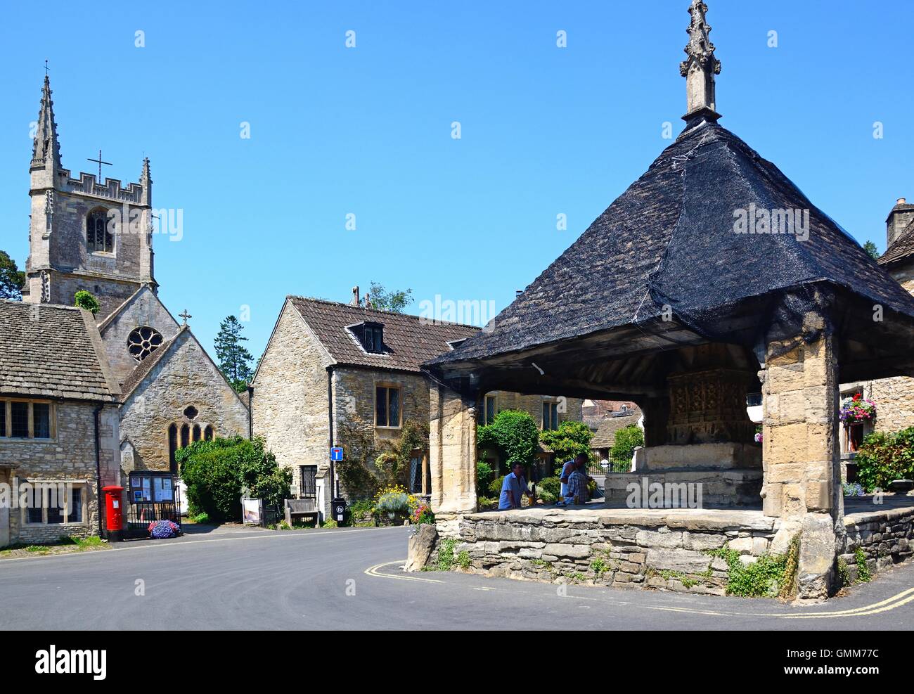 View of the fourteenth century market cross in the village centre with St Andrews church to the rear, Castle Combe, UK. Stock Photo