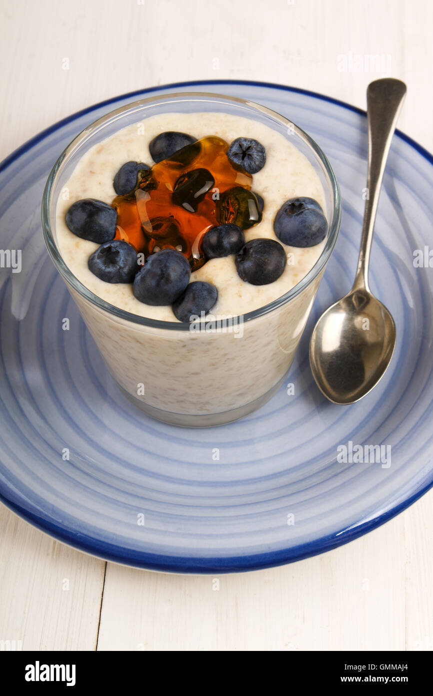 irish steel cut oats cooked with cream and blueberries in a dessert glass on blue plate Stock Photo
