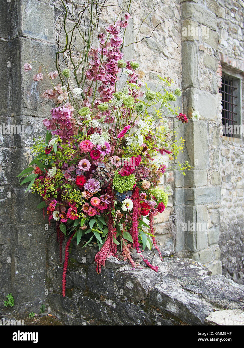 Outdoor floral arrangement, pastel shades. Against old grey stone building. Stock Photo