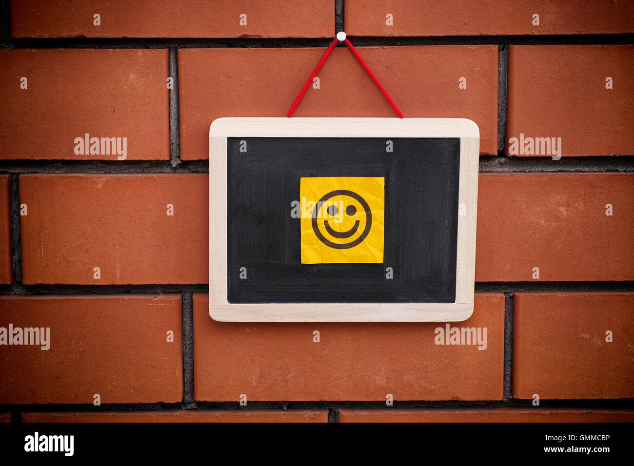 Paper note with happy face on blackboard. Close up. Stock Photo
