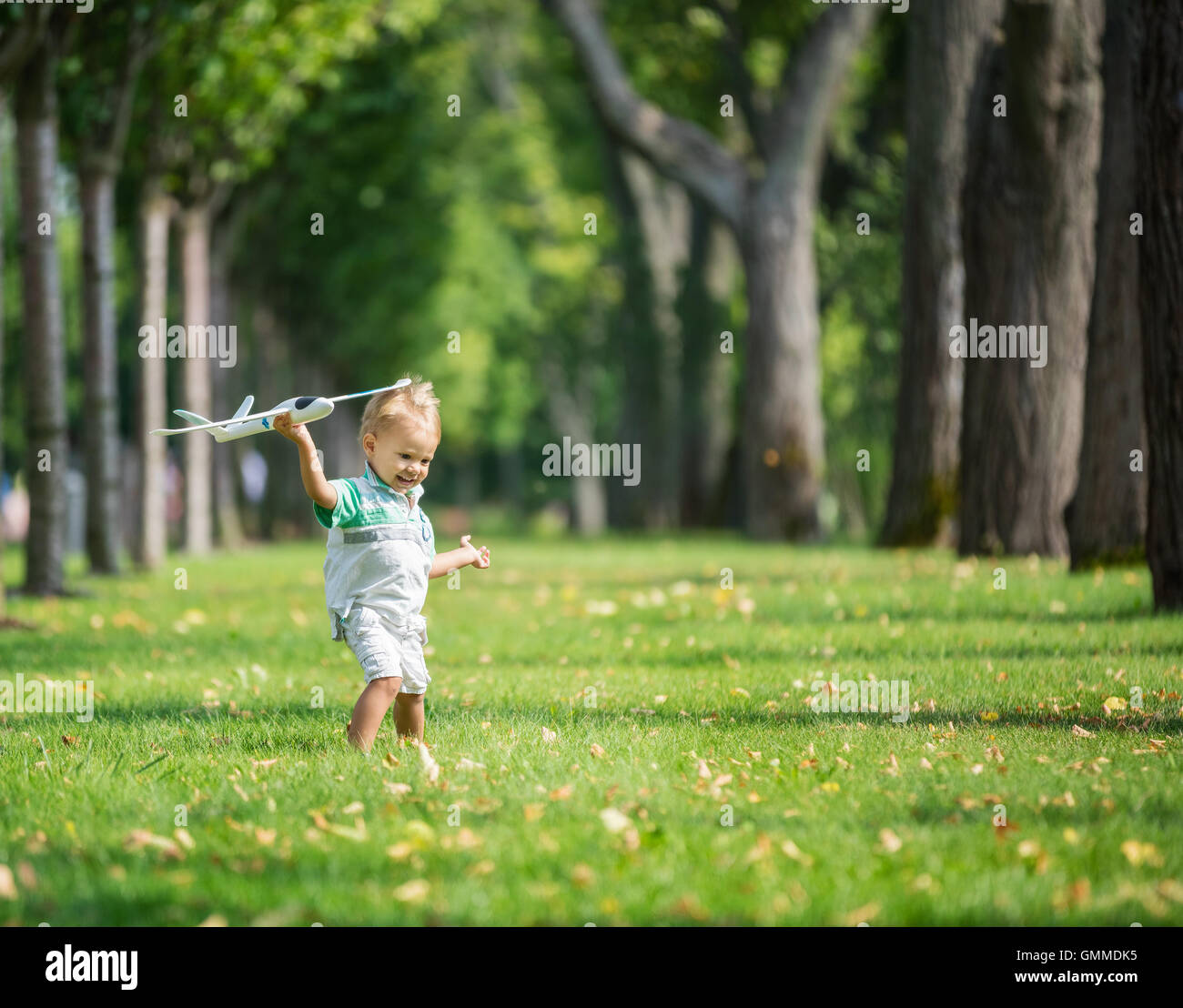 Toddler boy playing with toy glider in park on summer day Stock Photo