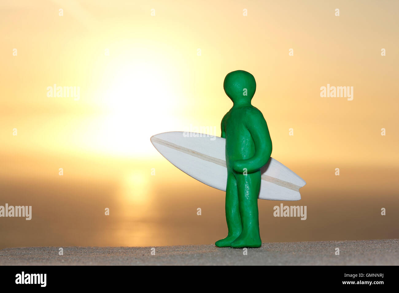 Plasticine Person and Balsa Wood Surfboard at Sunset Stock Photo