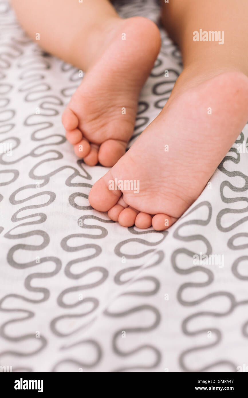 Barefoot baby on bedspread Stock Photo Alamy