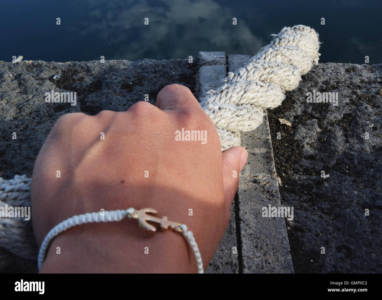 Personal view of woman's hand holding a boat rope, bracelet with anchor sign Stock Photo