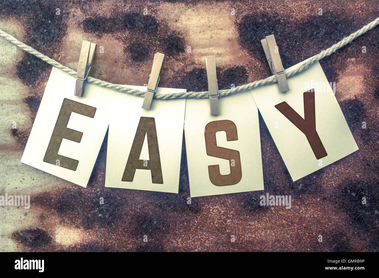 The word "EASY" stamped on cards and pinned to an old piece of twine