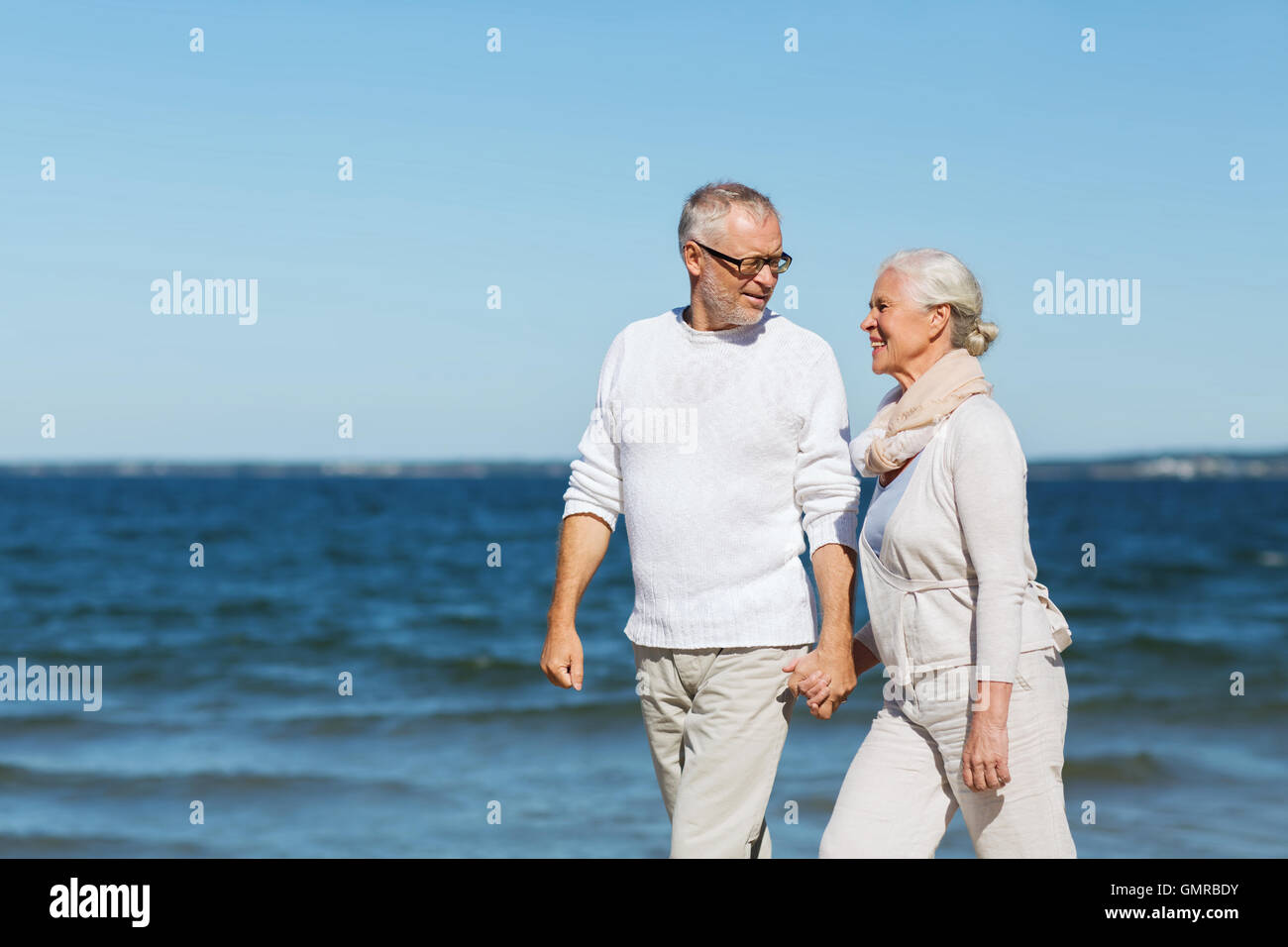 happy senior couple holding hands on summer beach Stock Photo - Alamy