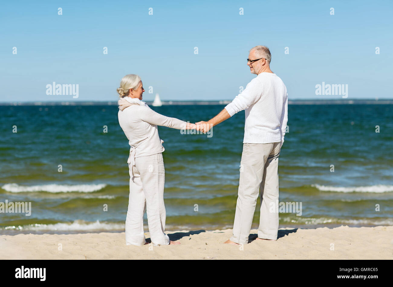 happy senior couple holding hands on summer beach Stock Photo - Alamy