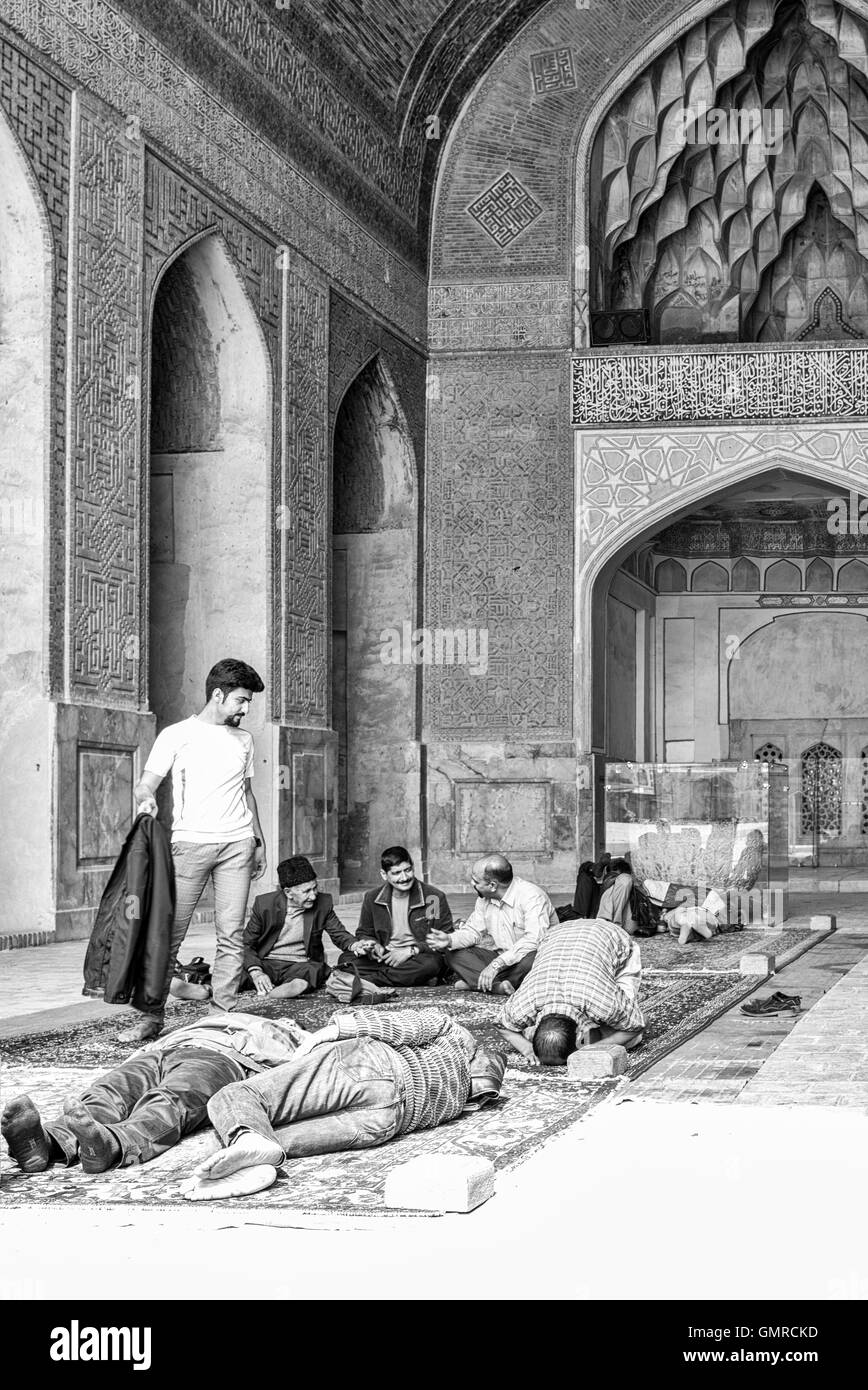 The Jāmeh Mosque of Isfahān is the grand, congregational mosque (Jāmeh) of Isfahān, Iran.  Men meet at noon for prayers, naps, and conversation. Monochrome. Stock Photo