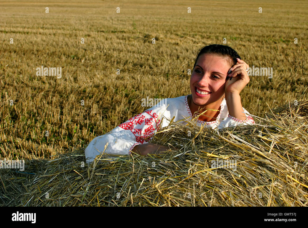 girl in traditional Russian costume lying on a haystack and smiling