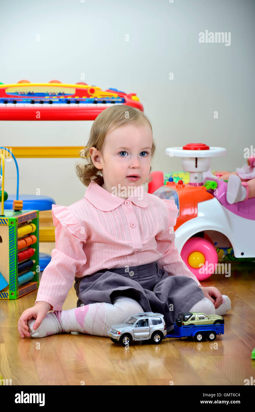 little girl in a room with toys, playing with cars Stock Photo - Alamy