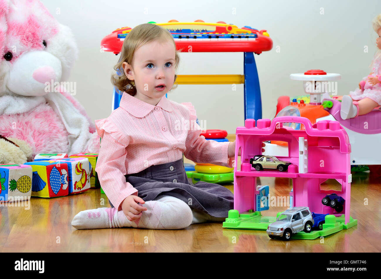 little girl in a room with toys, playing with cars Stock Photo - Alamy