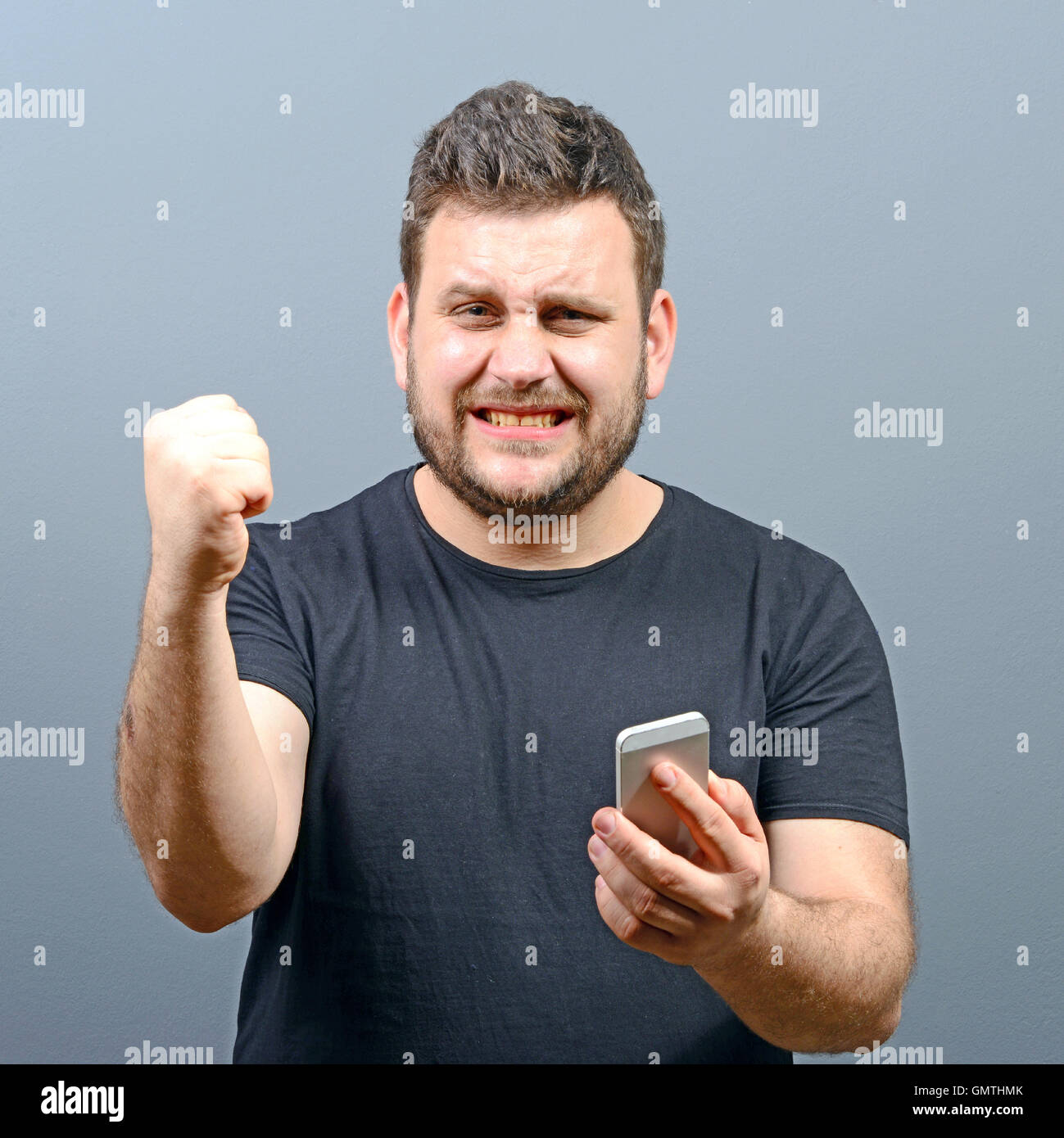 Portrait of ecstatic man holding cell phone and celebrating with closed ...