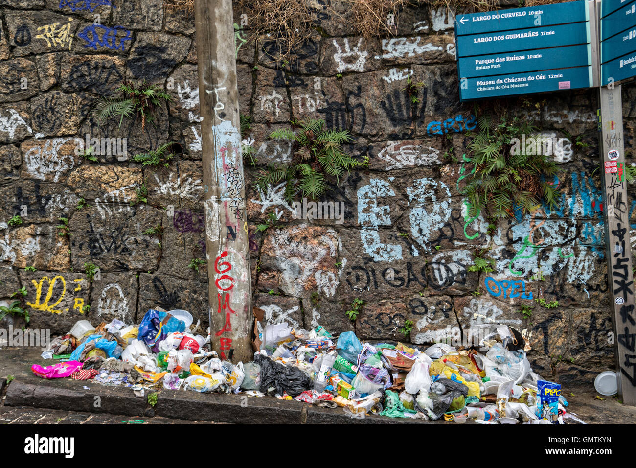 Trash piles up along a street along a graffiti wall in the Santa Teresa neighborhood in Rio de Janeiro, Brazil. Stock Photo