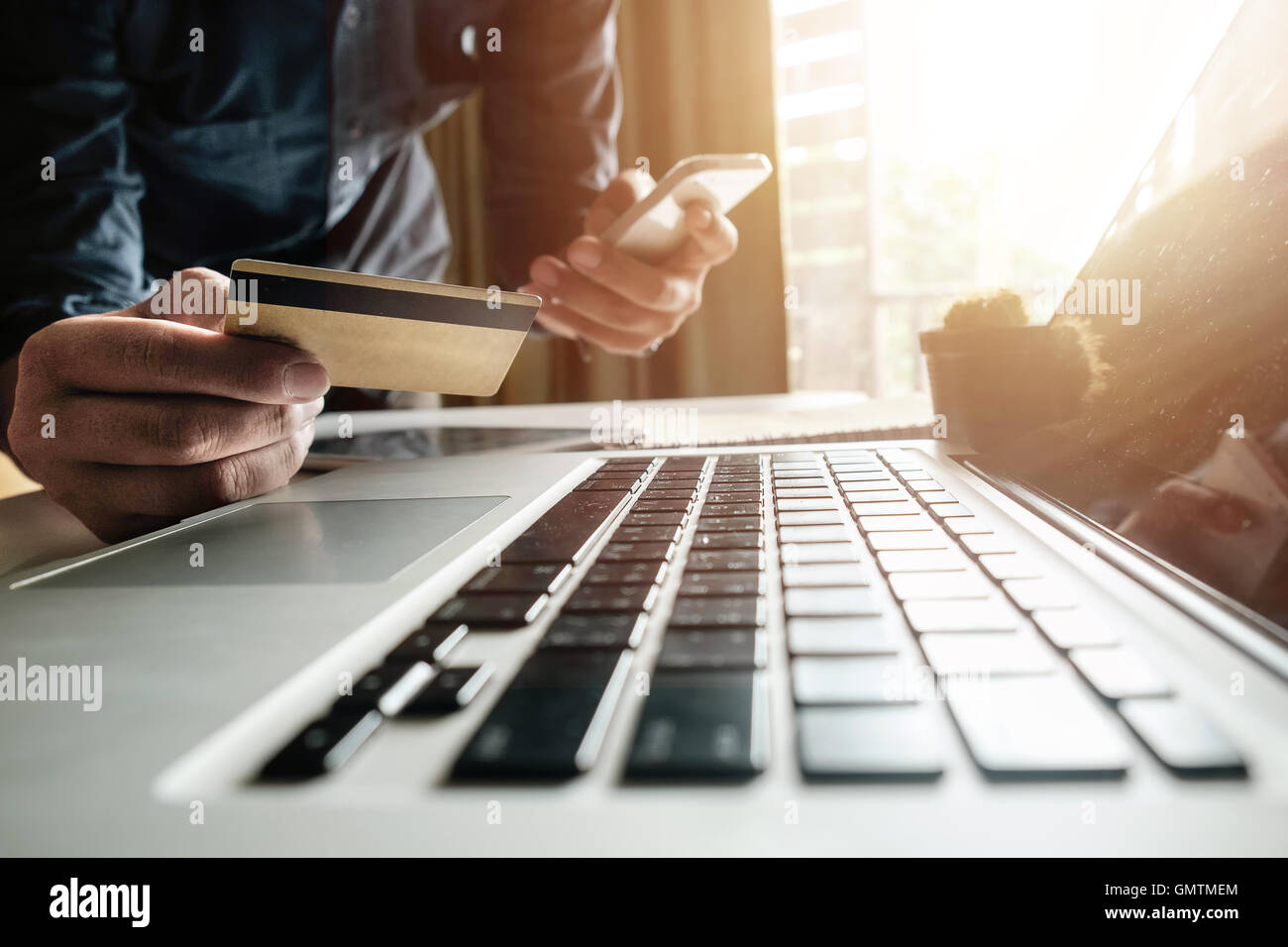Man hands using smartphone laptop and holding credit card with social media as Online shopping concept in morning light Stock Photo