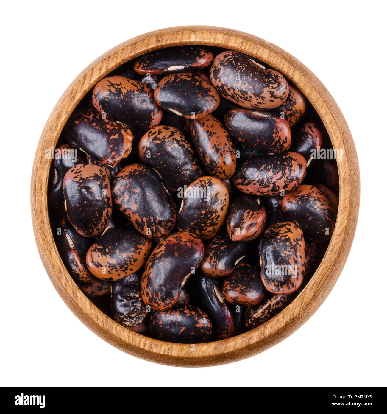 Black speckled kidney beans in a wooden bowl over white. Variety of common beans, Phaseolus vulgaris. Dried seeds. Stock Photo