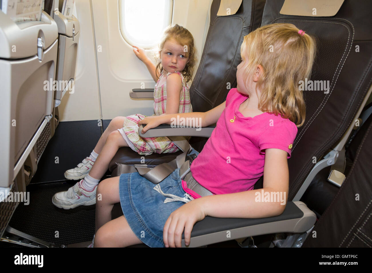 Child / children / two sisters aged 6 and 4 going on holiday / vacation / flying on an air plane / airplane / aeroplane flight Stock Photo