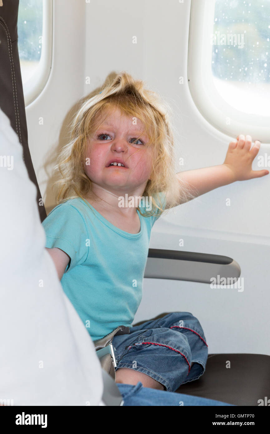 Baby toddler child age two, with tantrum, going on holiday / vacation / flying on Airbus air plane / airplane / aeroplane flight Stock Photo