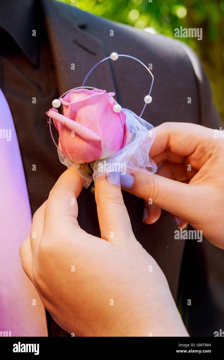 Bride pins a boutonniere to groom's blue jacket flowers on the groom's jacket Stock Photo