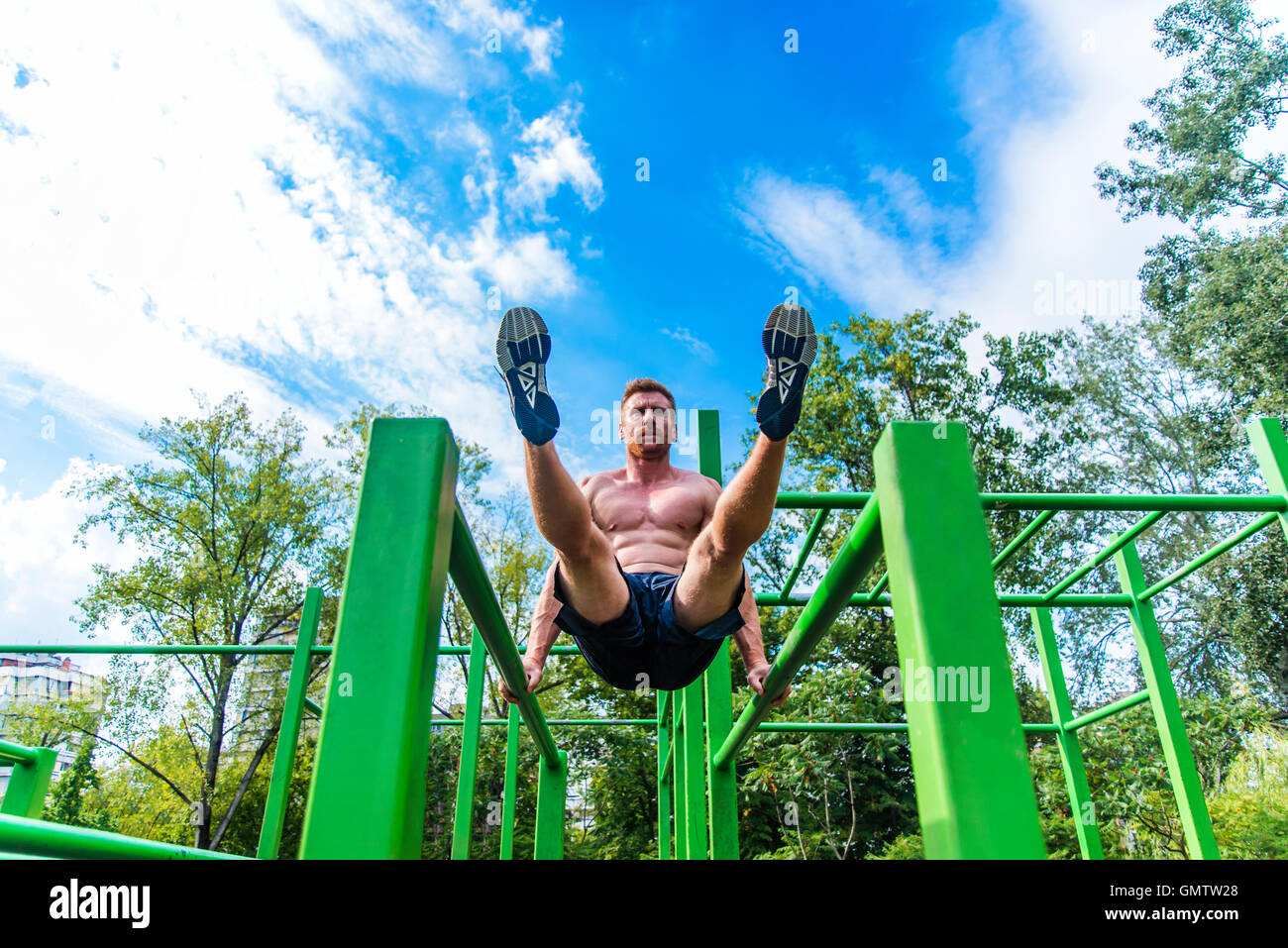 Young man doing pull ups on horizontal bar outdoors Stock Photo - Alamy