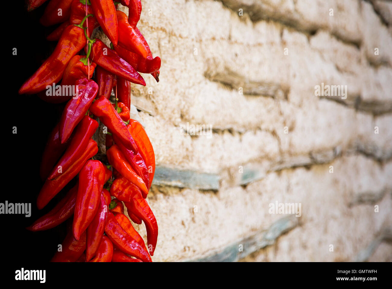 Red Paprika Peppers traditionally hanging To Dry On The Wall Of A House Stock Photo