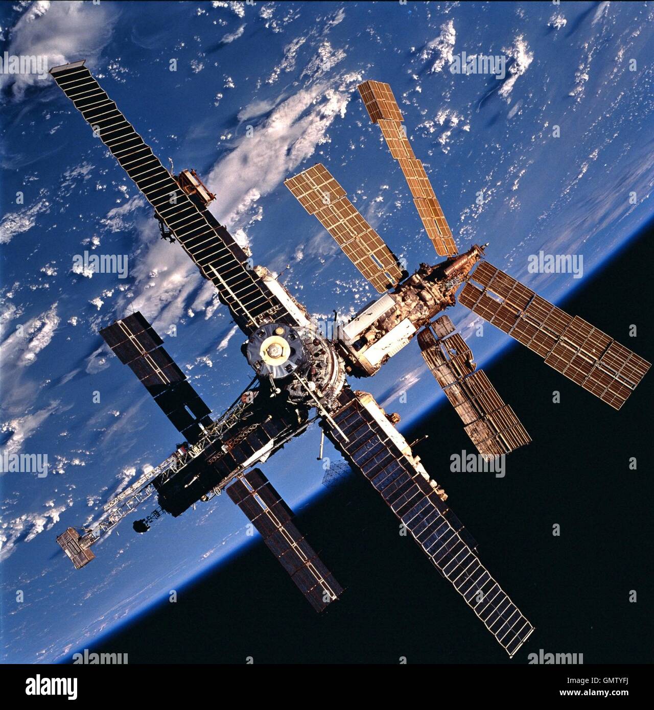 View of Russian Mir Space Station backdropped against a cloud-covered Earth was photographed during a fly-around by the Space Shuttle Atlantis following the conclusion of joint docking activities between the Mir-24 and STS-86 crews October 5, 1997. One of the solar array panels on the Spektr Module shows damage incurred during the impact of a Russian unmanned Progress re-supply ship which collided with the space station June 25, 1997. Mir is nearing the end of its existence as Russia plans to steer the craft out of orbit in late February 2001 in a controlled crash to dump the space station saf Stock Photo