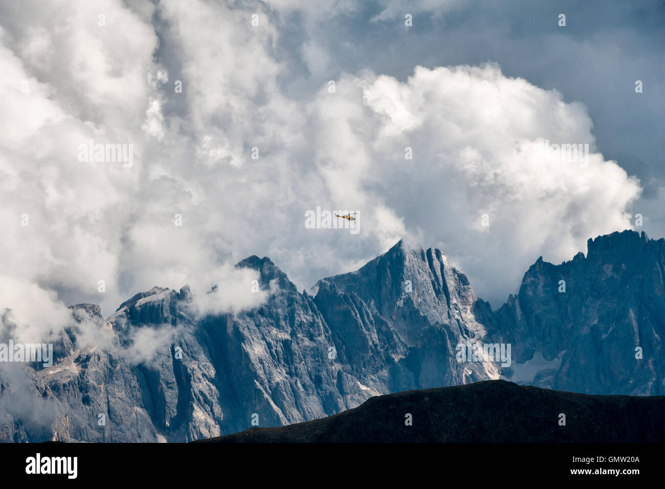 The Dolomites, Trentino, northern Italy. A mountain rescue helicopter flies over the peaks of Pale di San Martino in bad weather Stock Photo