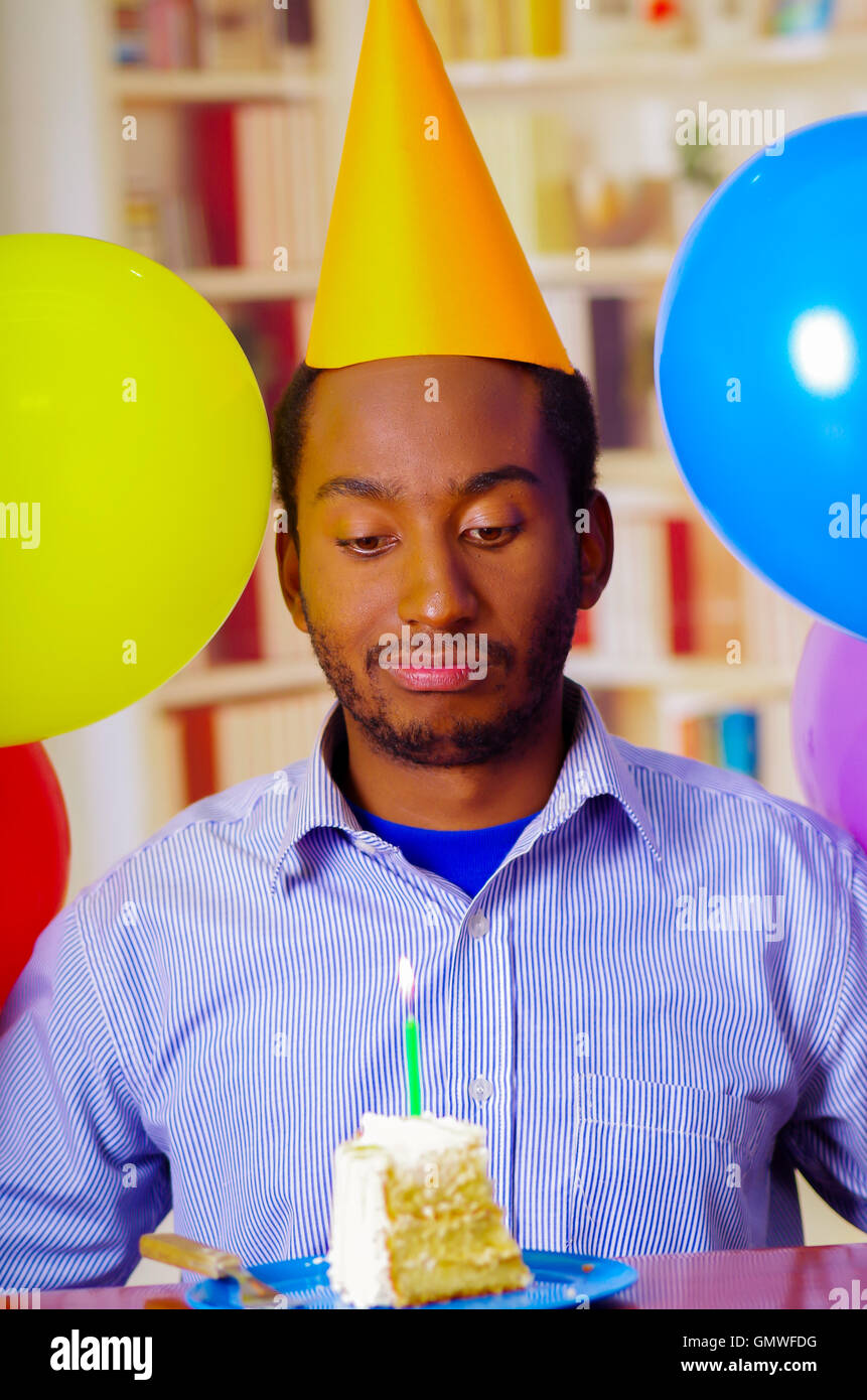 Good looking man wearing blue shirt and yellow party hat sitting by table  staring at piece of cake in front, celebrating alone concept Stock Photo -  Alamy