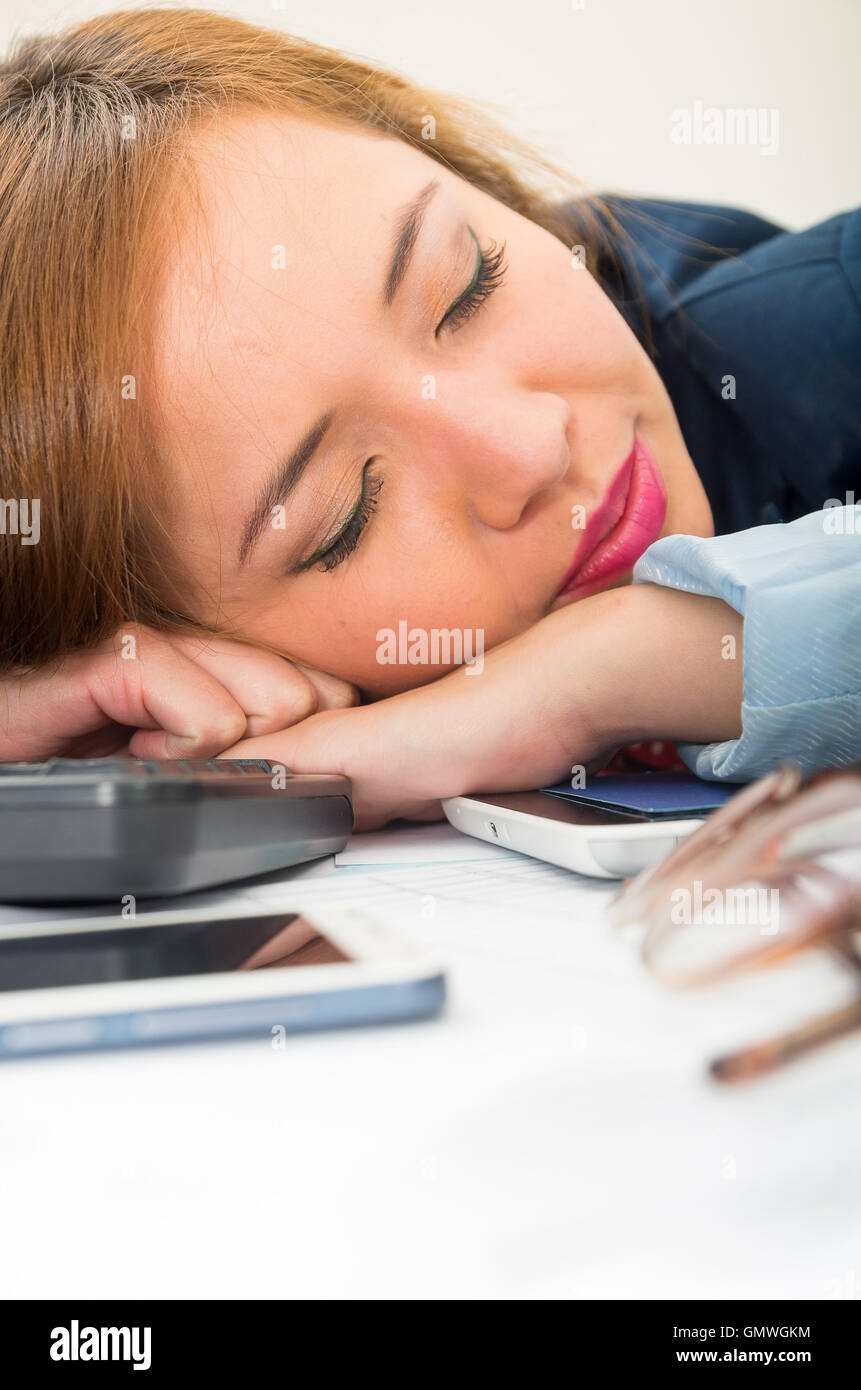 Office woman bent over white desk resting or sleeping with computer keyboard, glasses and mobile spread out Stock Photo