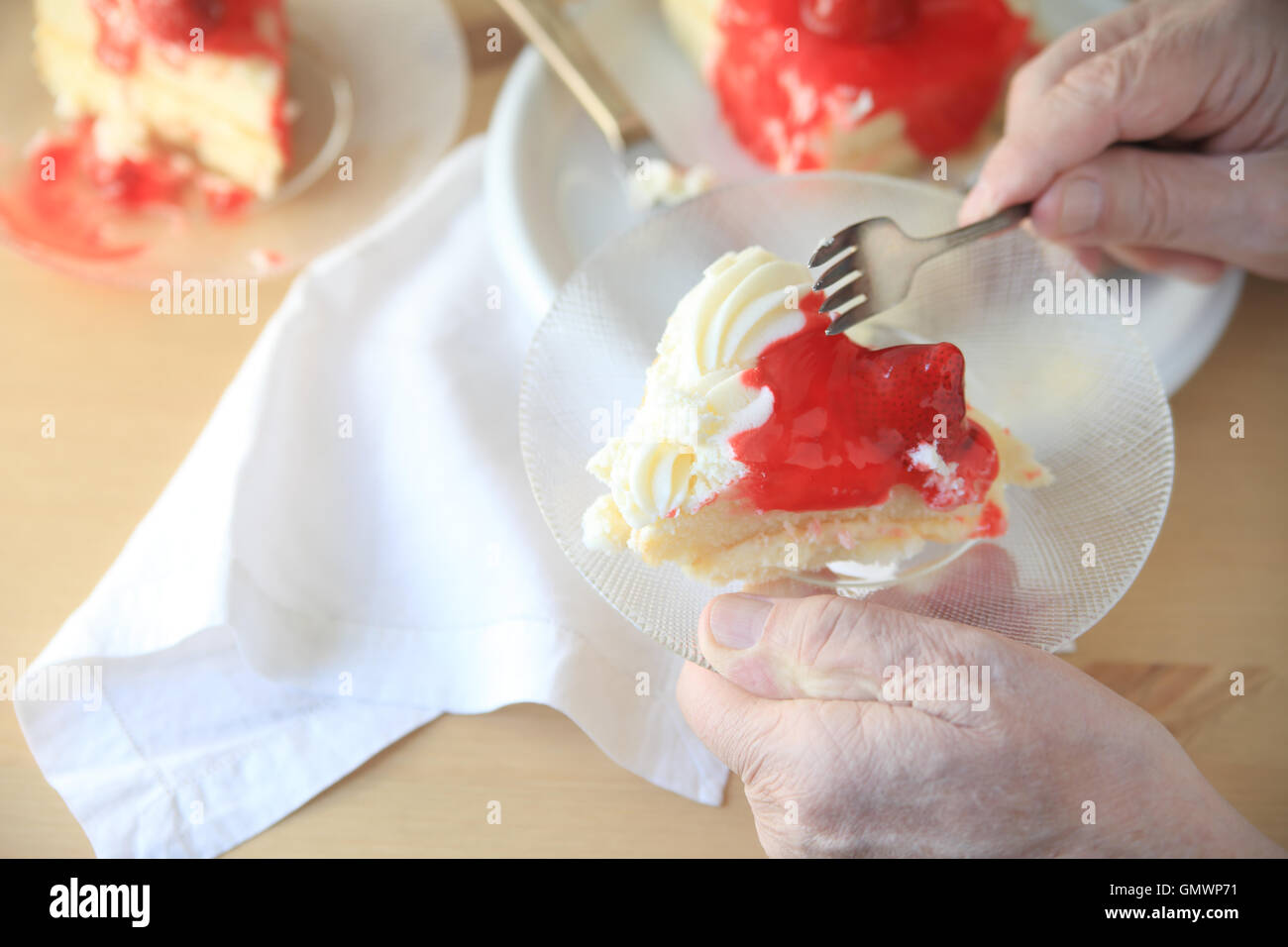 Man holds glass dish with portion of cake with whipped cream and strawberry glaze. Stock Photo