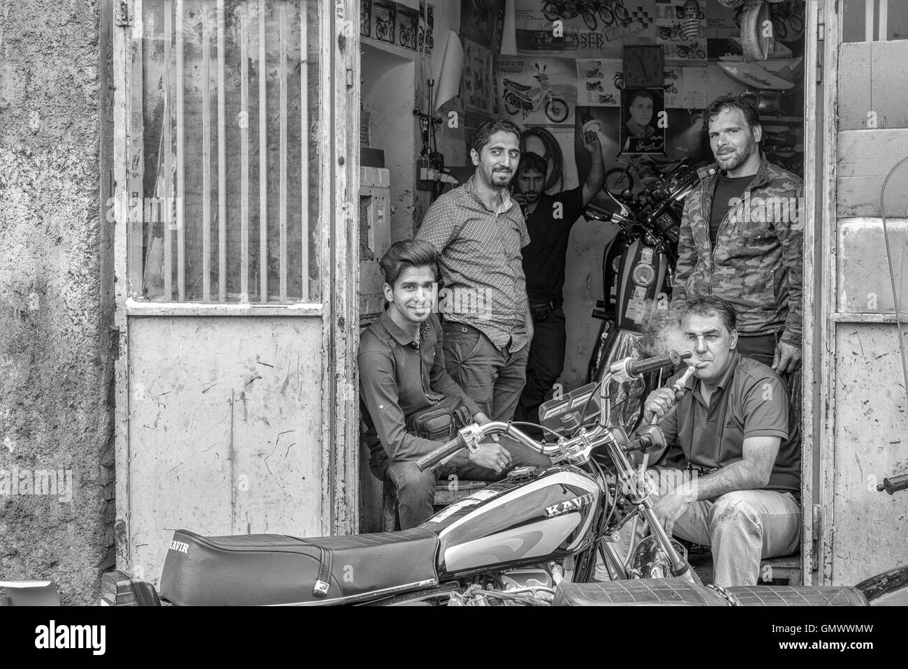 Friends hanging out at motorbike repair shop in Isfahan, Iran. Monochrome. Stock Photo