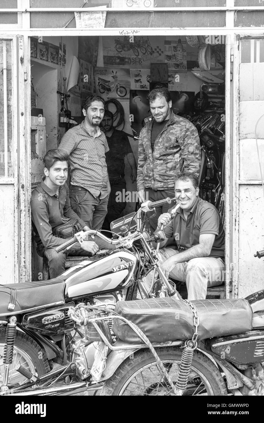 Friends hanging out at motorbike repair shop in Isfahan, Iran. Monochrome. Stock Photo