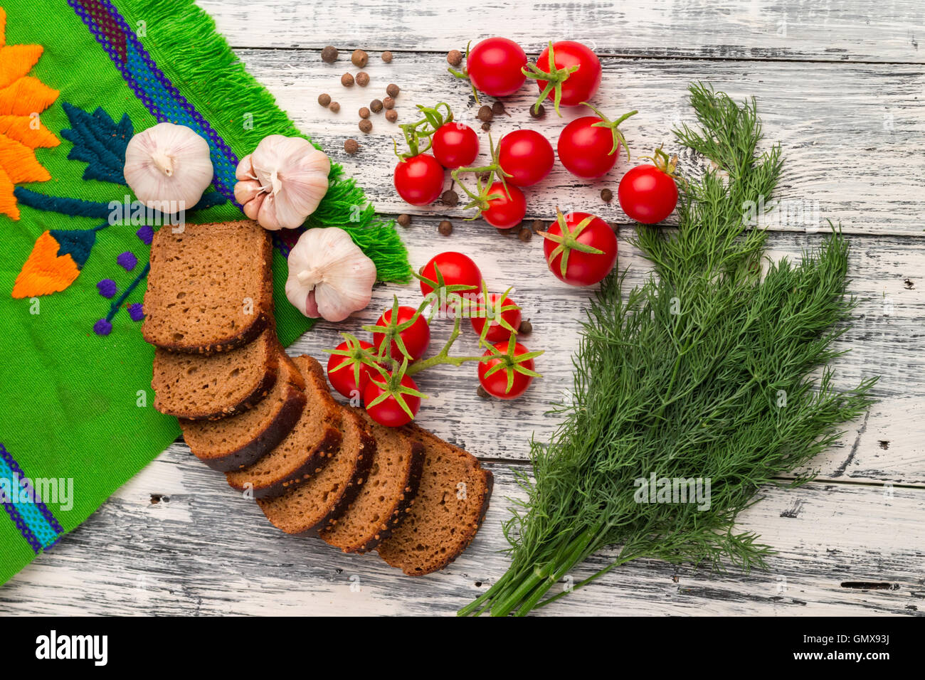 Still life on wooden background: tomatoes, black bread, garlic, fennel, bayberry pepper Stock Photo