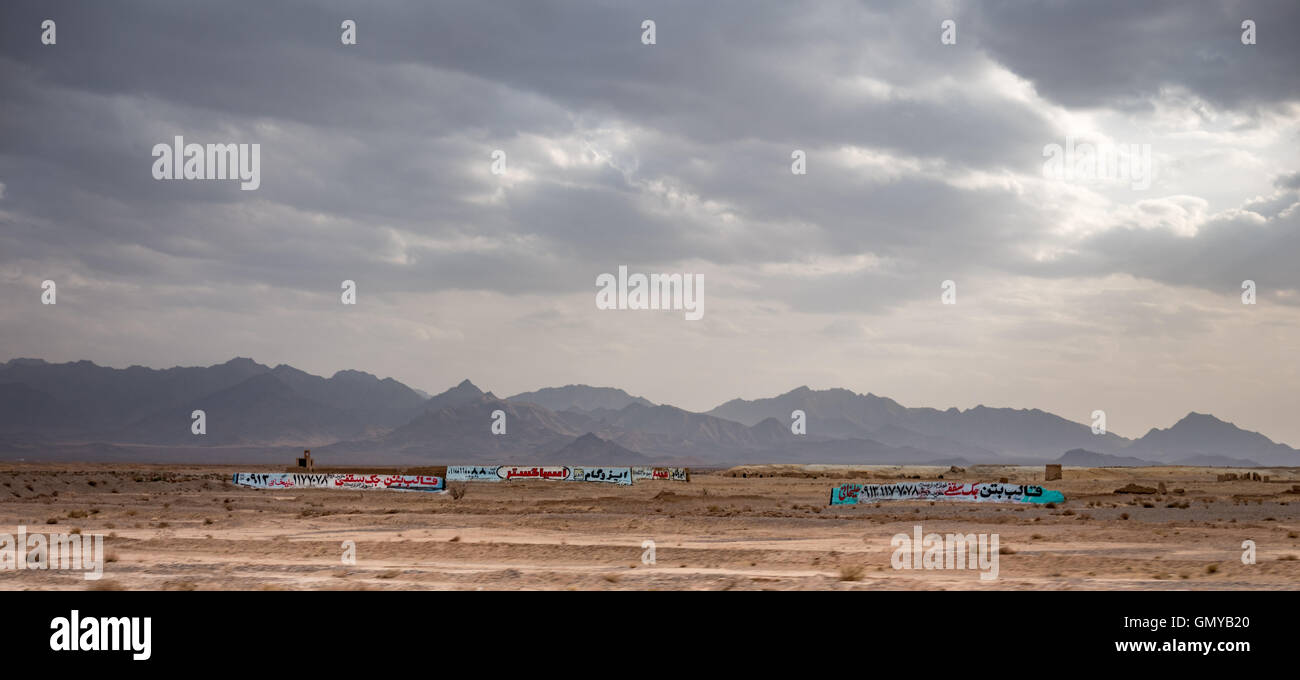 Mountains and desert with Farsi signs on abandoned walls and buildings