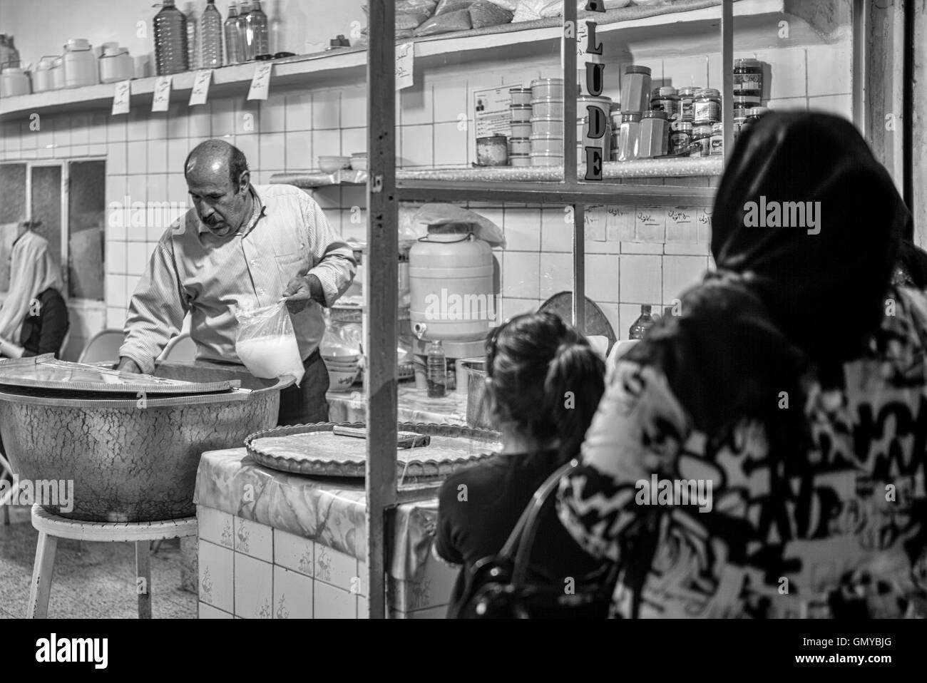 Crowd waiting outside popular faloodeh shop for the sweet noodle dessert in Yazd, Iran. Black and white night street scene. Stock Photo