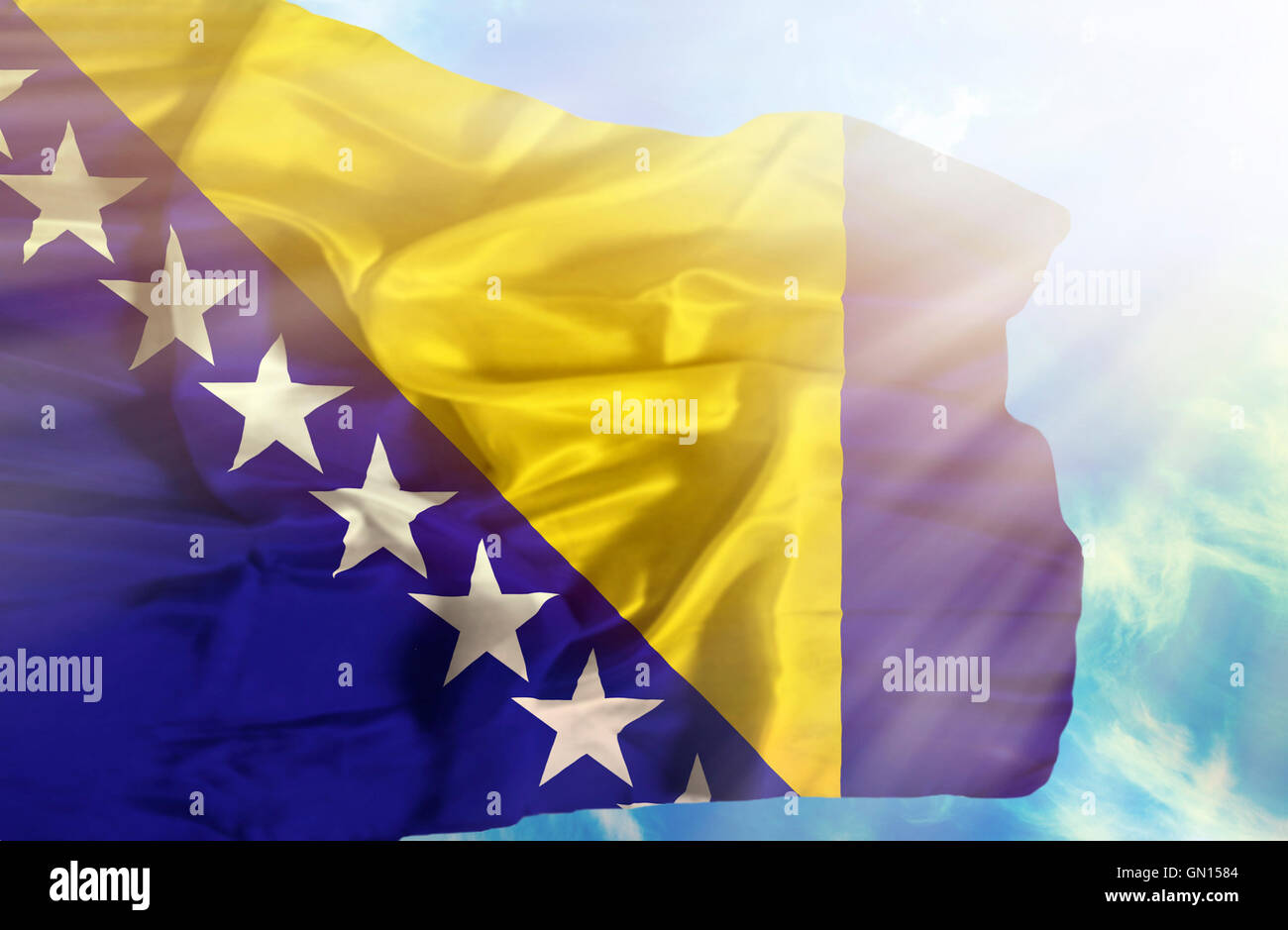 Bosnia and Herzegovina waving flag against blue sky with sunrays Stock ...