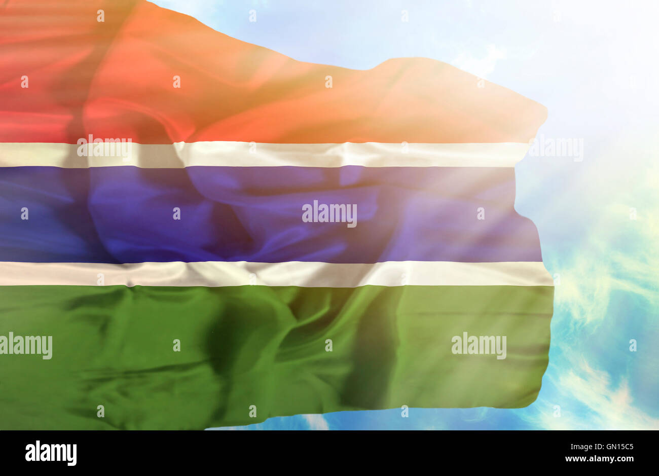 Gambia waving flag against blue sky with sunrays Stock Photo - Alamy