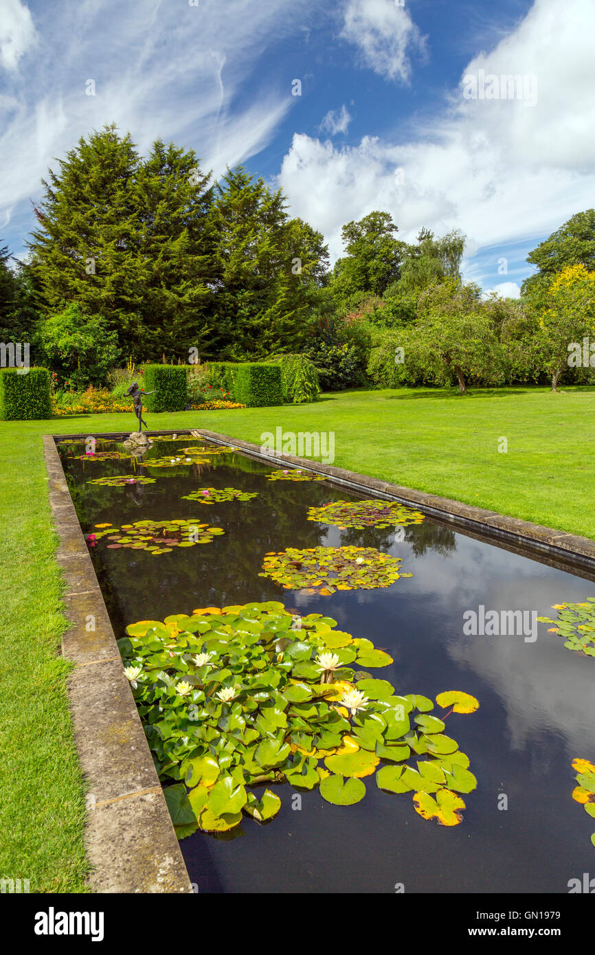 The colourful water lily pond with a statue of young girl at Waterperry Gardens, Oxfordshire, England, UK Stock Photo