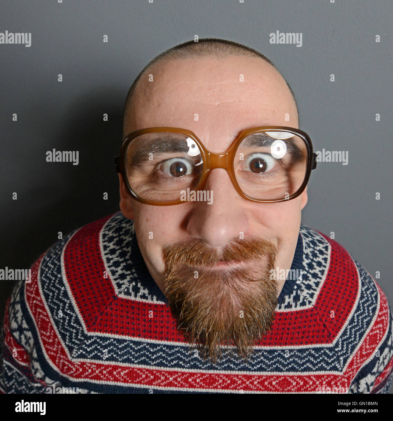 Portrait of a nerd with glasses and retro sweater against gray