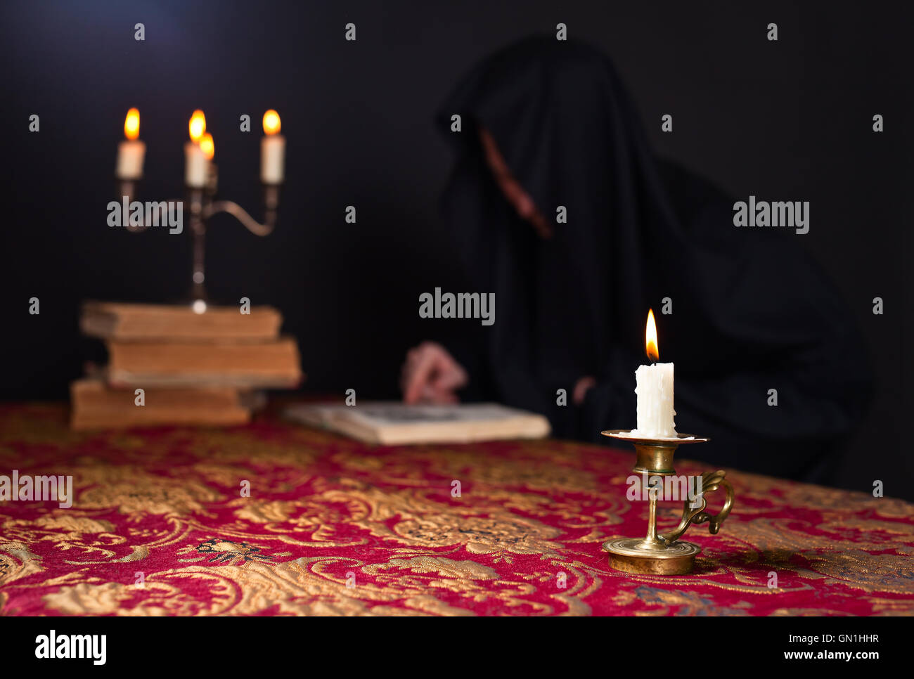 Candle on the background of the reading monk Stock Photo