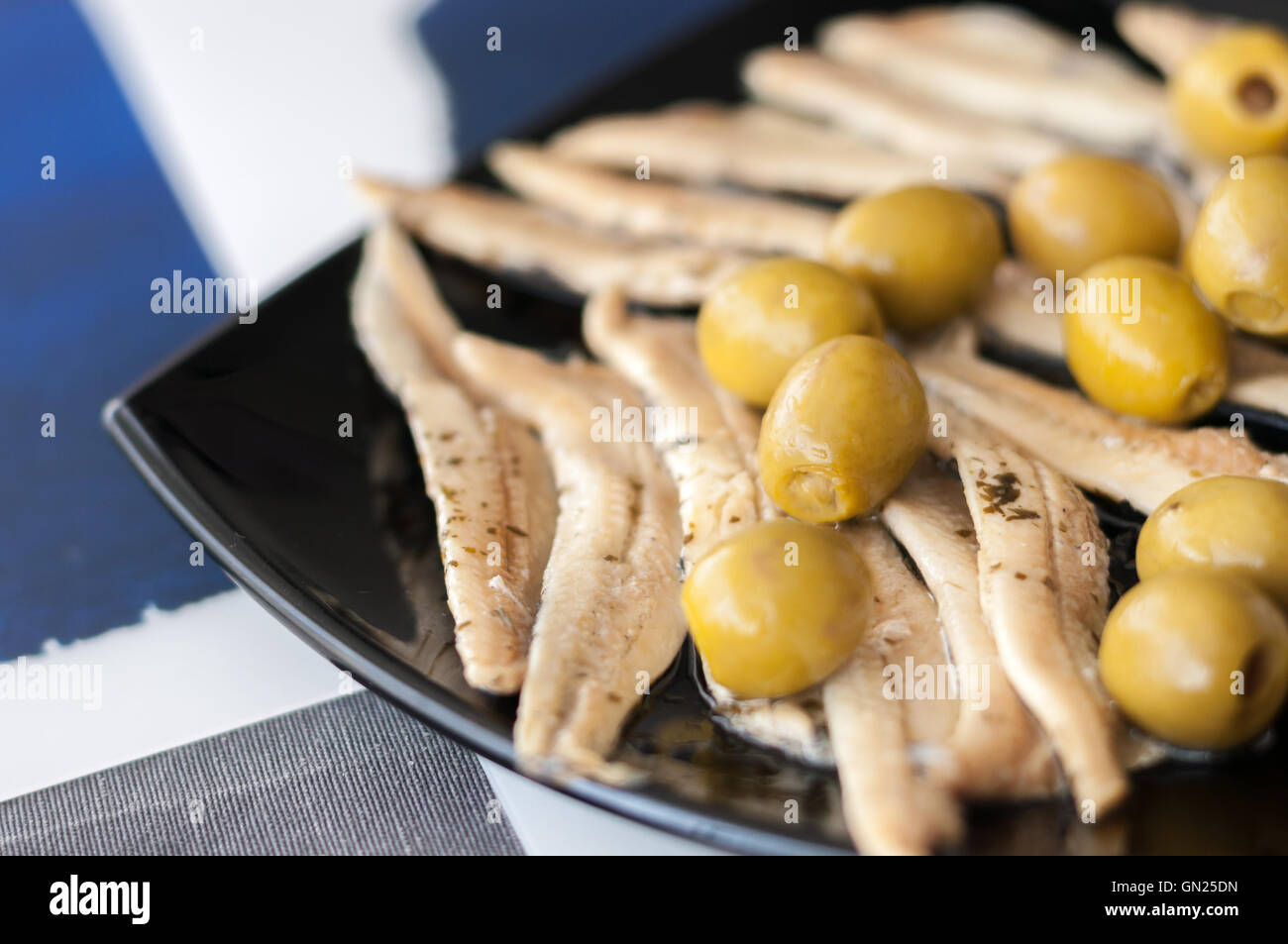 Marinated anchovies and olives on the plate, a traditional snack in