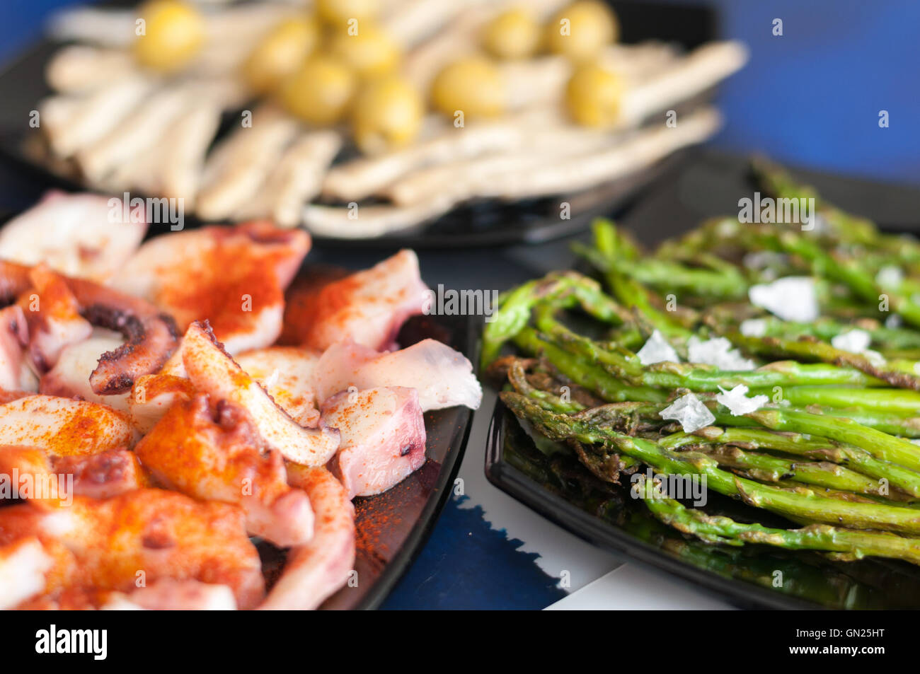 octopus, anchovies, olives, asparagus and coarse salt on plates