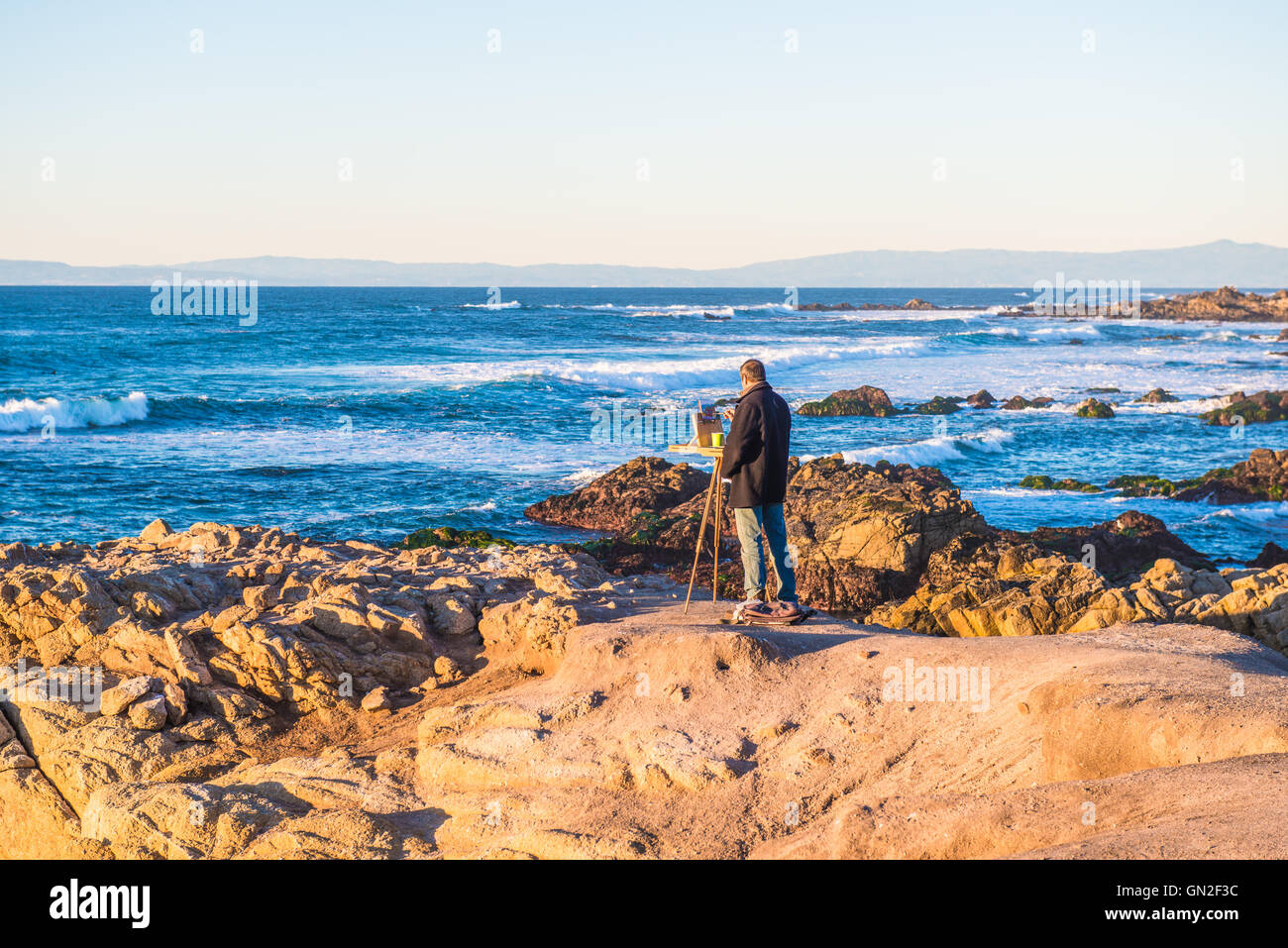 Artist painting on the rocks ocean Stock Photo - Alamy