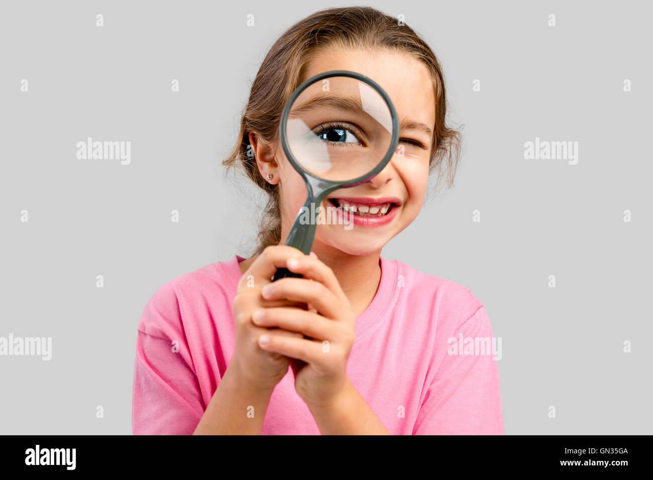 Cute little girl looking through a magnifying glass Stock Photo