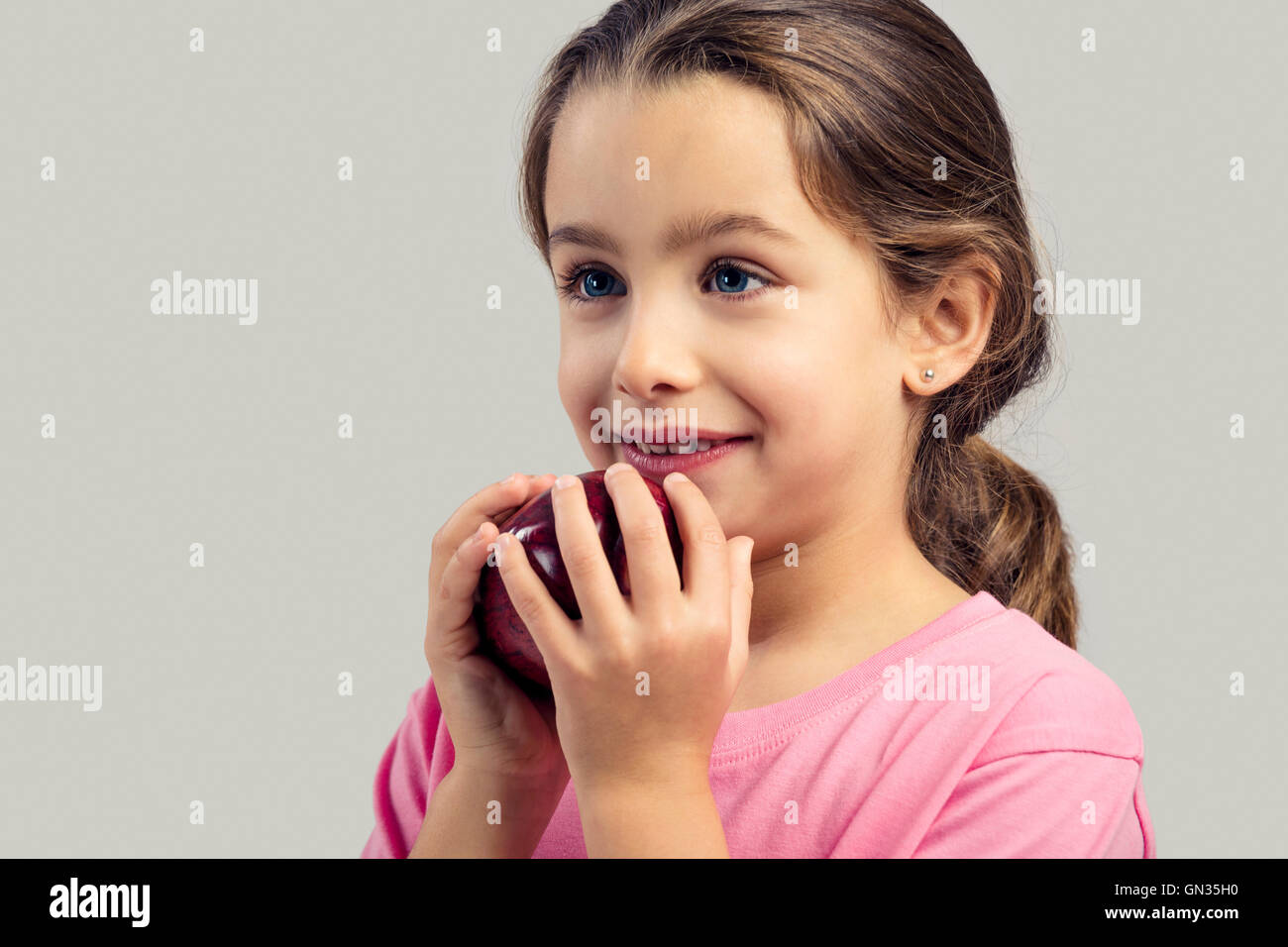 Studio portrait of a beautiful little girl holding a fresh red apple Stock Photo